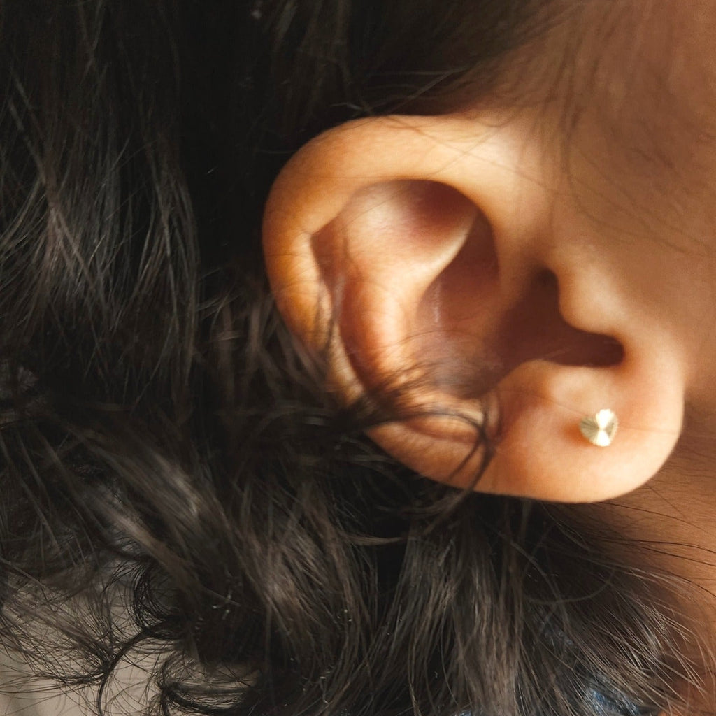 Close up of gold heart stud earrings in little girl's ear