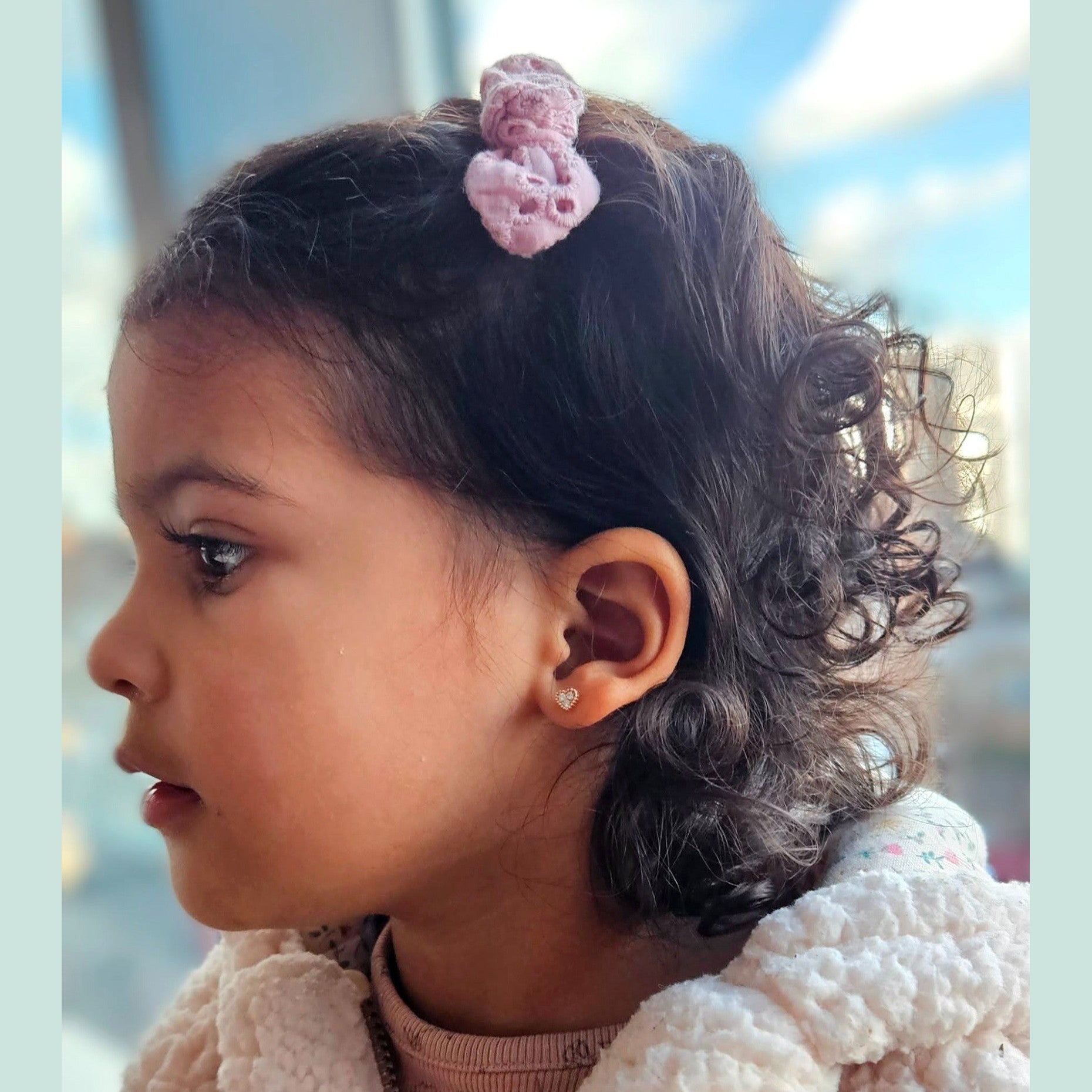 Young girl with a pink hair clip looking to the side with diamond stud earring
