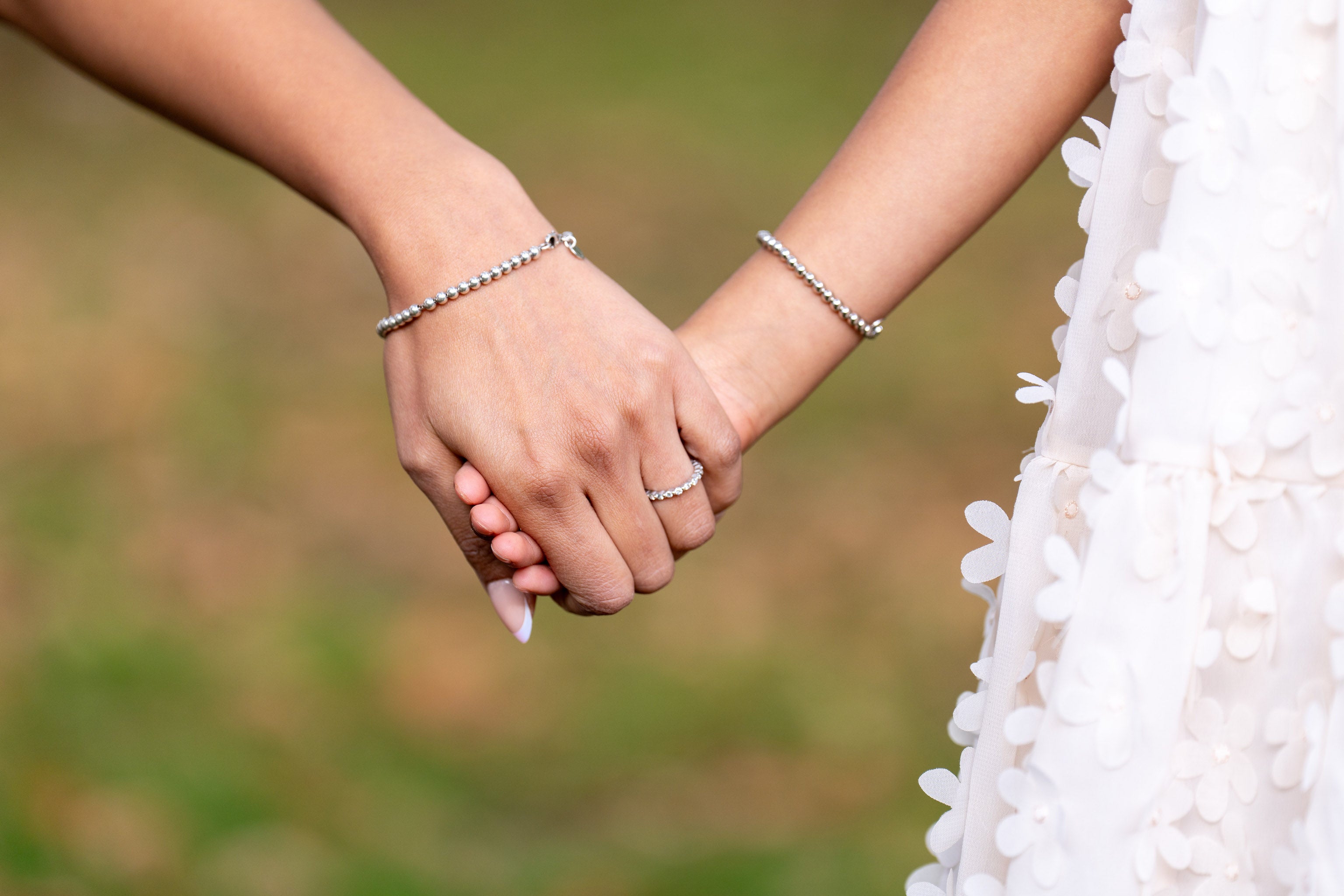 Two hands holding each other with a blurred natural background