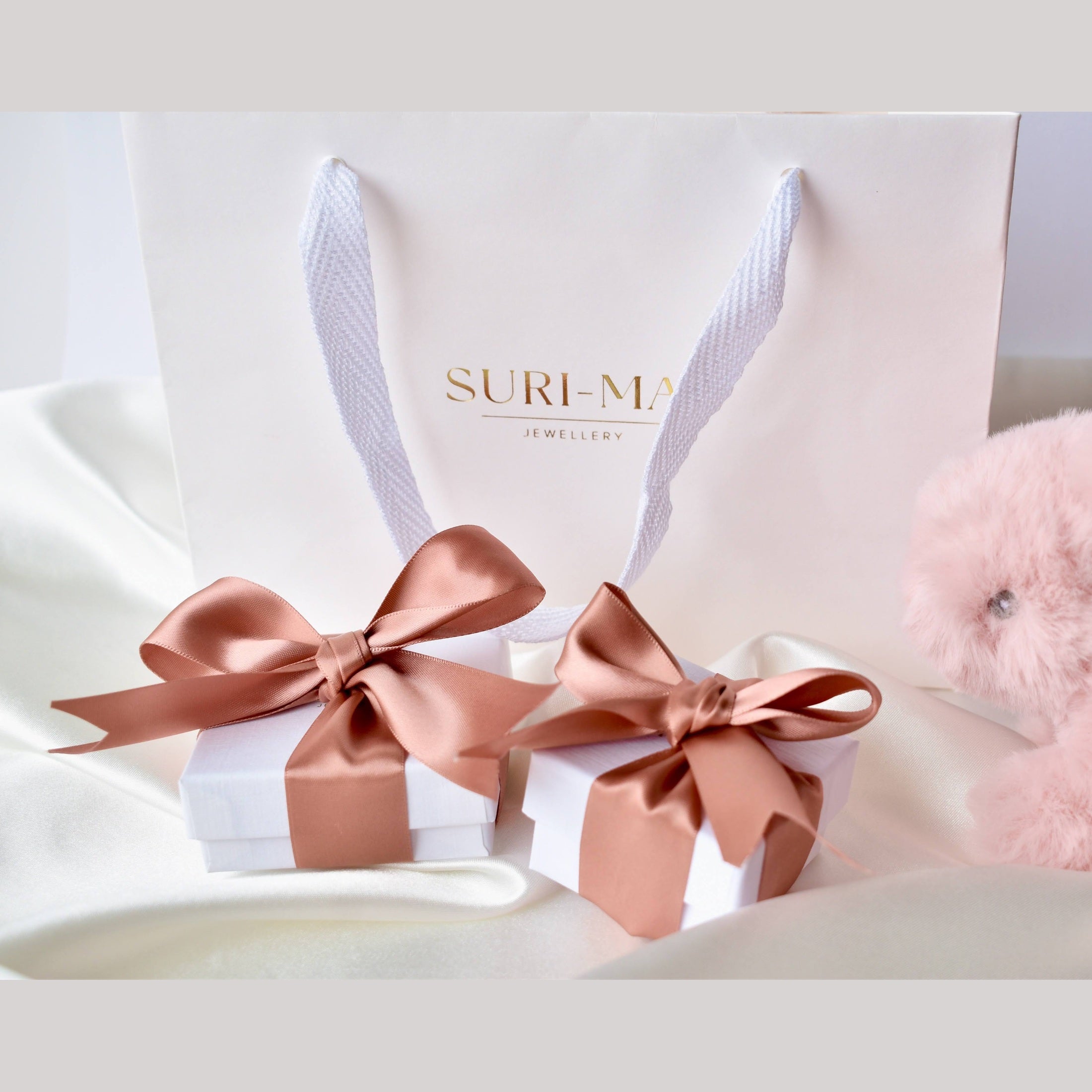 Gift box with pink ribbon and 'Suri-Mai' branding on a white gift bag