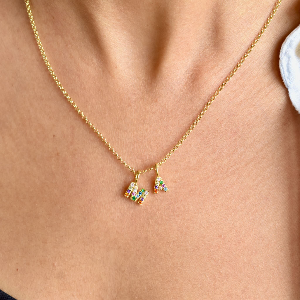 Gold necklace with two letter pendants with colourful stones around neck