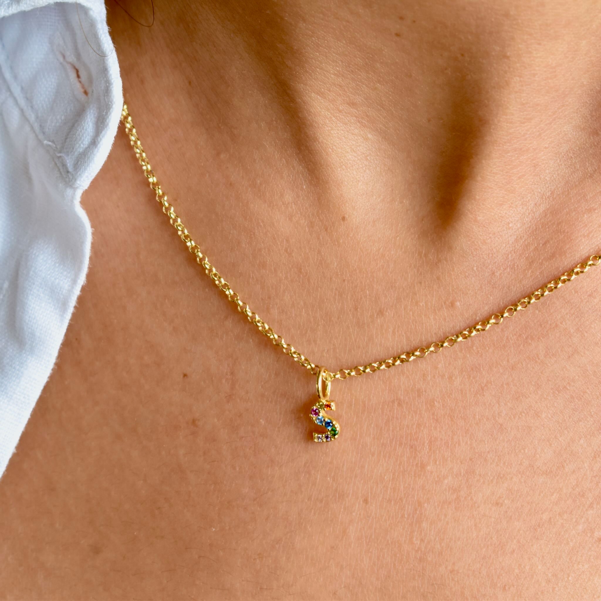 Gold necklace with colourful letter S pedant with rainbow stones around neck