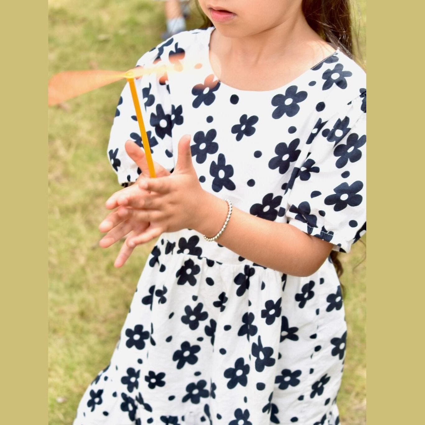 Child wearing a white dress with black floral pattern outdoors