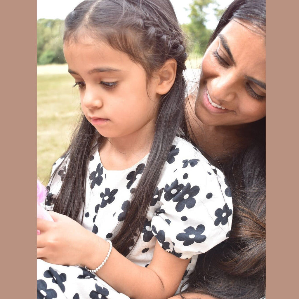 Woman and young girl sitting together outdoors, smiling.